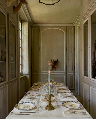 antique table in a french chateau with grey walls and antique plates 