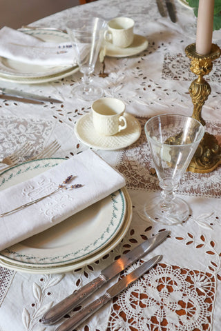 Elegant table setting with woven tablecloth, creamware plates and antique silver knives by Maison Fete.