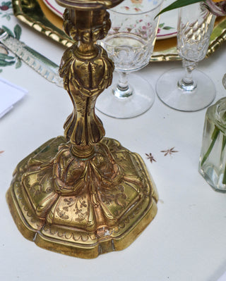 Close-up of antique French gilt bronze candlestick base showing hand-chased rococo scrollwork and acanthus leaf detail