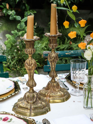 Pair of antique French gilt bronze candlesticks with lit beeswax tapers, showing fluted stem and campana drip pan