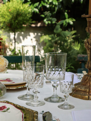 Antique French cut crystal glassware suite with faceted stems, four graduated sizes, styled outdoors with antique china and gilt candlesticks