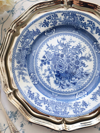 Single chinoiserie transferware plate shown face-on, centred floral basket motif with dense floral border